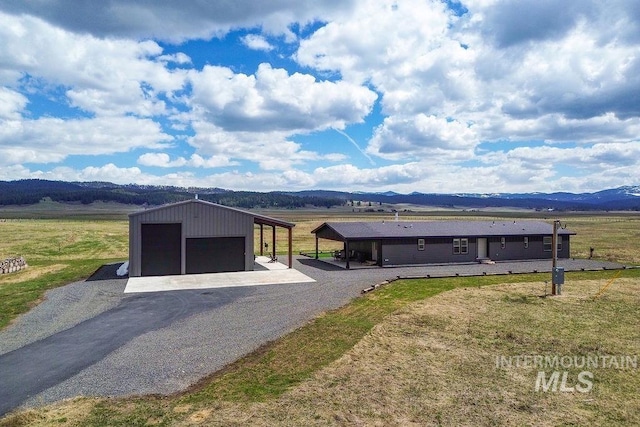 view of front facade featuring a detached garage, an outbuilding, a mountain view, and a front lawn