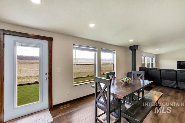 dining space with dark wood-style flooring, visible vents, a wood stove, baseboards, and recessed lighting