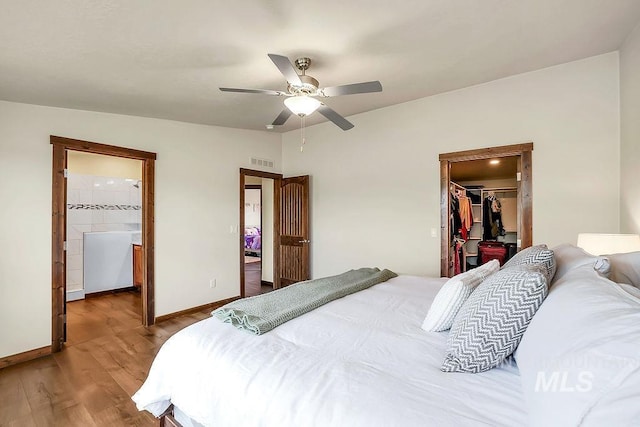 bedroom featuring visible vents, a closet, wood finished floors, baseboards, and a walk in closet