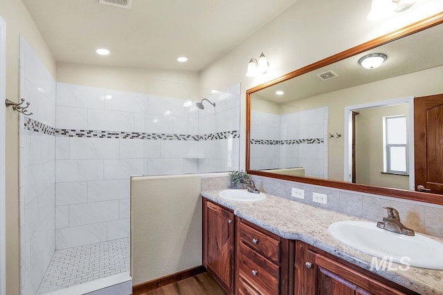 full bathroom with visible vents, a sink, walk in shower, and double vanity