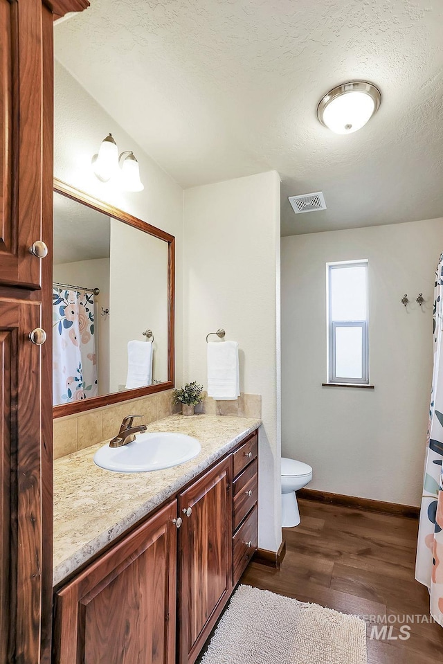 bathroom with visible vents, wood finished floors, vanity, baseboards, and toilet