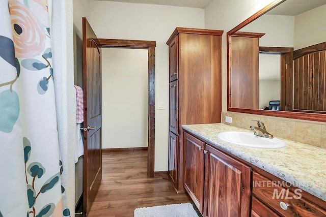 bathroom featuring vanity, baseboards, backsplash, and wood finished floors
