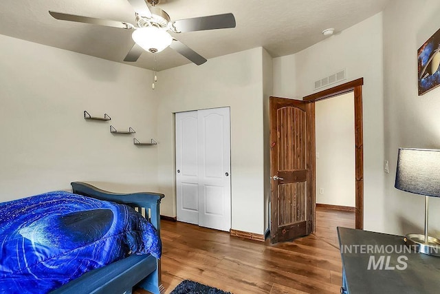 bedroom with a ceiling fan, wood finished floors, and visible vents