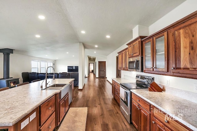 kitchen with a sink, dark wood-style floors, open floor plan, glass insert cabinets, and stainless steel appliances