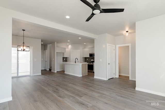 4403 N Magical Creek Ave, Meridian, ID 83646 - unfurnished living room featuring light wood-type flooring, a ceiling fan, baseboards, and a sink