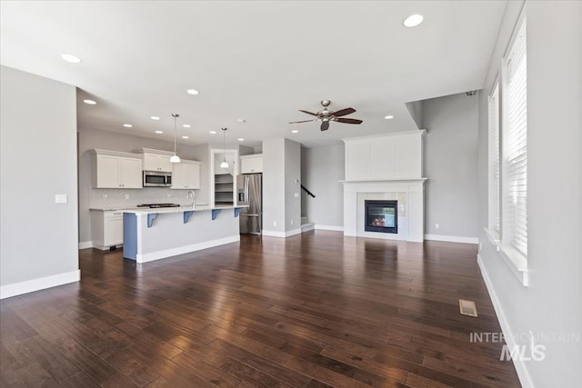 3631 S Pheasant Tail Way, Boise, ID 83716 - unfurnished living room with a ceiling fan, recessed lighting, dark wood-type flooring, a sink, and a tile fireplace