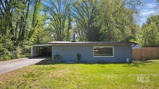 view of side of property featuring stucco siding, driveway, a chimney, and fence