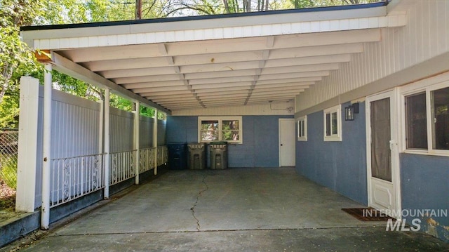 view of parking / parking lot with fence and an attached carport