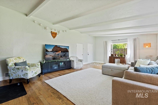 living area featuring baseboards, beam ceiling, and wood finished floors