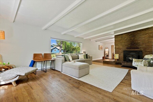living area featuring wood finished floors, baseboards, beam ceiling, and a fireplace