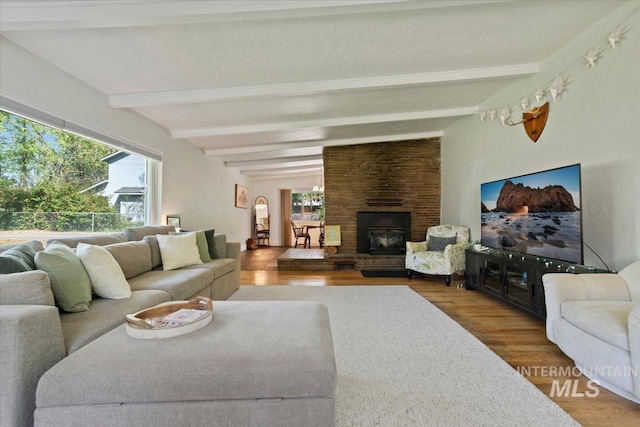 living area featuring beamed ceiling and wood finished floors