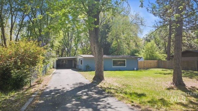 view of front of property with fence, aphalt driveway, stucco siding, an attached carport, and a front yard