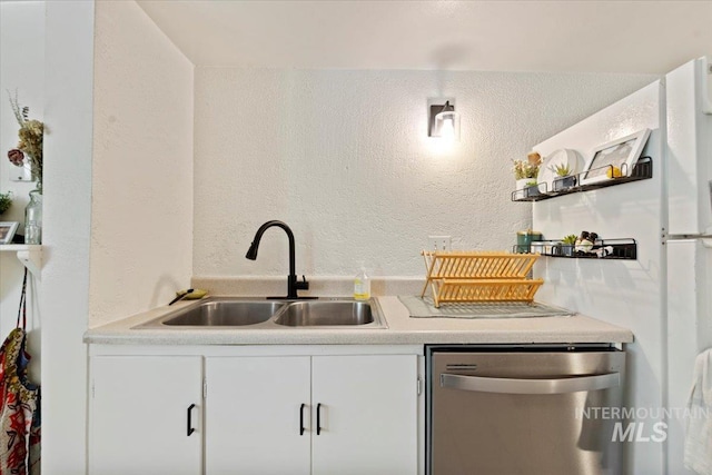 bar featuring a sink, a textured wall, and stainless steel dishwasher