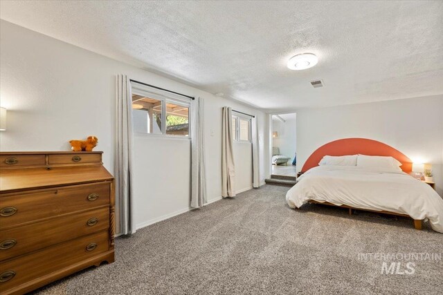 bedroom featuring visible vents, carpet flooring, a textured ceiling, and baseboards
