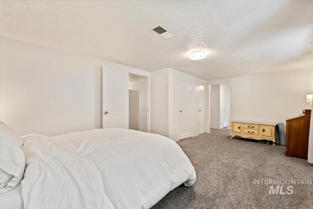 bedroom featuring a textured ceiling, visible vents, and carpet
