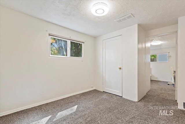 unfurnished bedroom with visible vents, carpet floors, a closet, baseboards, and a textured ceiling