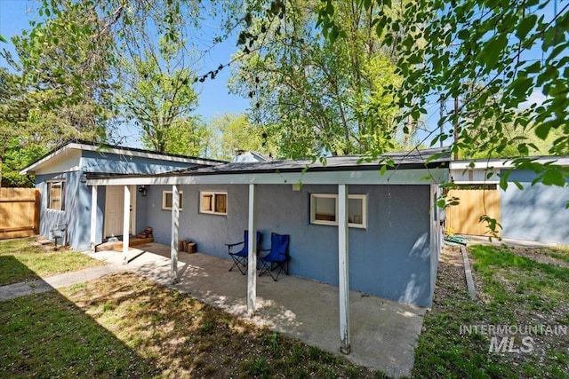 rear view of property with stucco siding, a patio area, and fence