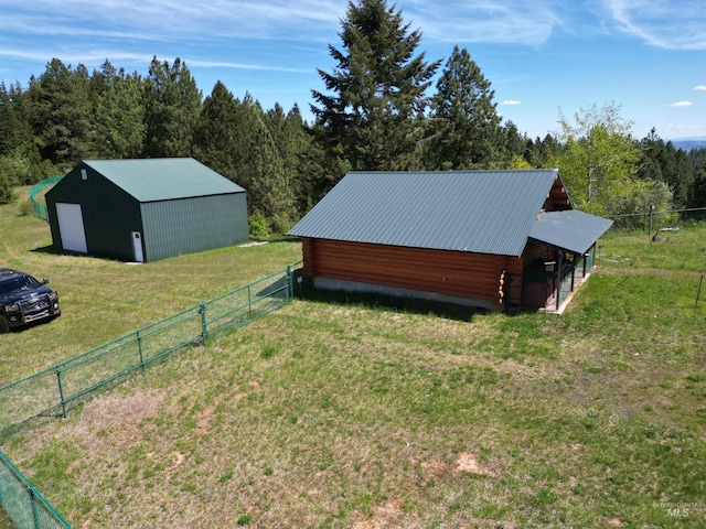 view of property exterior featuring a pole building, log exterior, an outdoor structure, metal roof, and a wooded view
