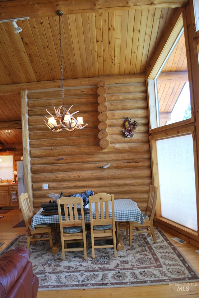 dining room with a chandelier, log walls, wooden ceiling, and hardwood / wood-style flooring