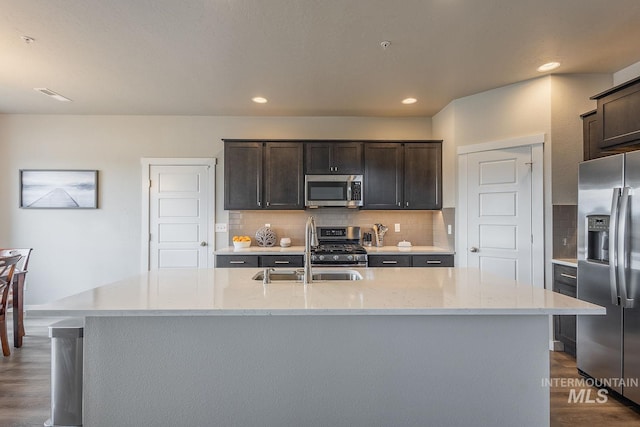 8228 S Bogus Ridge Ave, Boise, ID 83716 - kitchen with stainless steel appliances, a sink, dark brown cabinetry, decorative backsplash, and light stone countertops