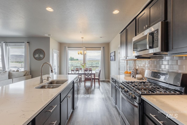 8228 S Bogus Ridge Ave, Boise, ID 83716 - kitchen with appliances with stainless steel finishes, a sink, light wood-style flooring, light stone counters, and decorative backsplash
