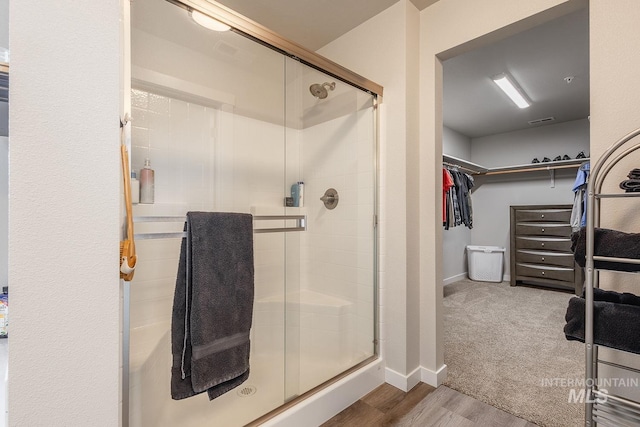 8228 S Bogus Ridge Ave, Boise, ID 83716 - bathroom featuring a stall shower, a walk in closet, wood finished floors, and baseboards