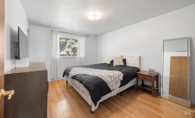 bedroom featuring light wood-style floors and a textured ceiling