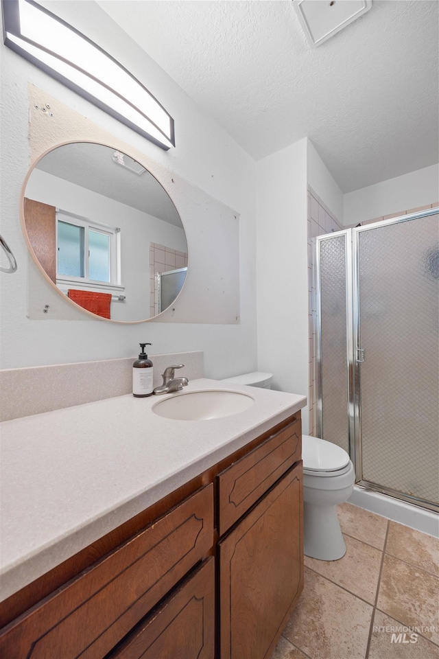 bathroom with toilet, a stall shower, a textured ceiling, tile patterned flooring, and vanity