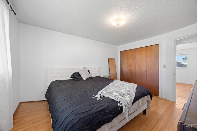 bedroom with a textured ceiling, a closet, and light wood-type flooring