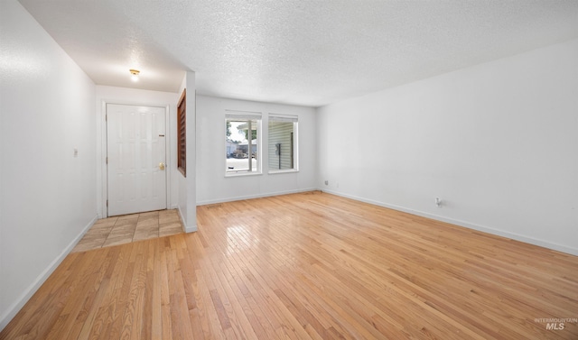 foyer with light wood finished floors, a textured ceiling, and baseboards