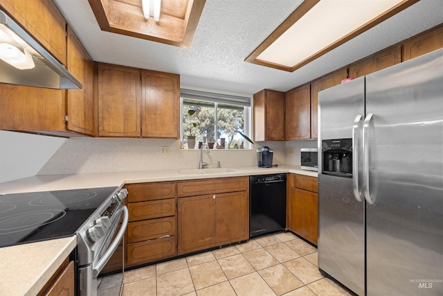 kitchen with a sink, brown cabinetry, stainless steel appliances, and under cabinet range hood