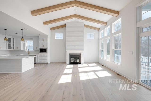 7927 W Rockhaven Dr, Eagle, ID 83616 - unfurnished living room featuring a fireplace with flush hearth, beam ceiling, light wood-style floors, and high vaulted ceiling