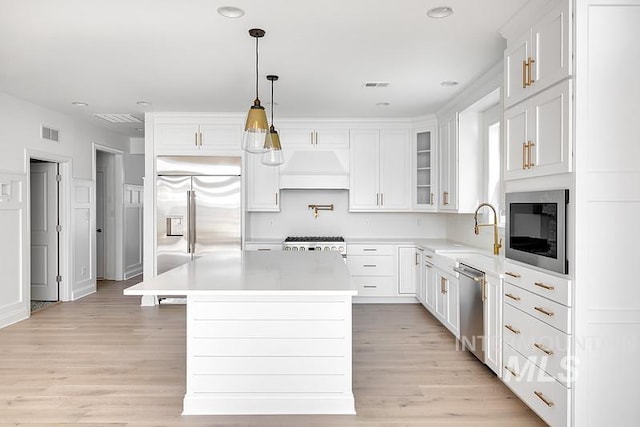 7927 W Rockhaven Dr, Eagle, ID 83616 - kitchen with built in appliances, custom range hood, light countertops, white cabinets, and a center island