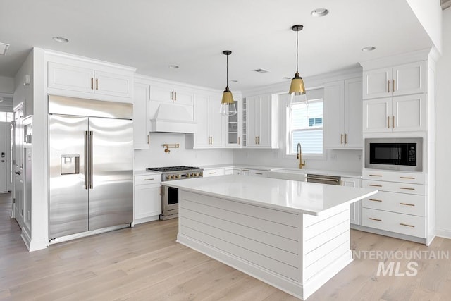 7927 W Rockhaven Dr, Eagle, ID 83616 - kitchen with built in appliances, custom range hood, light countertops, light wood-style floors, and white cabinets