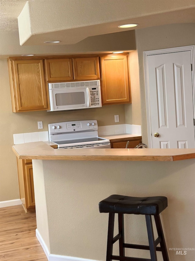 851 W Florida, Nampa, ID 83686 - kitchen featuring white appliances, a kitchen breakfast bar, light wood-style flooring, light countertops, and baseboards