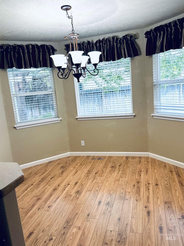 851 W Florida, Nampa, ID 83686 - unfurnished dining area with a chandelier, wood finished floors, a textured ceiling, and baseboards