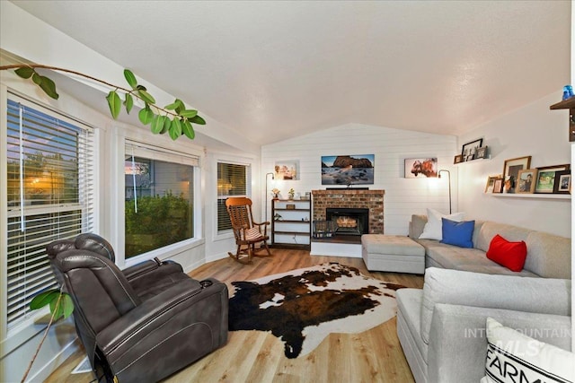 living area with baseboards, wood finished floors, vaulted ceiling, and a fireplace