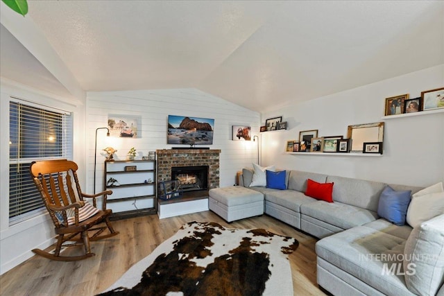 living area with wooden walls, a fireplace, wood finished floors, and lofted ceiling