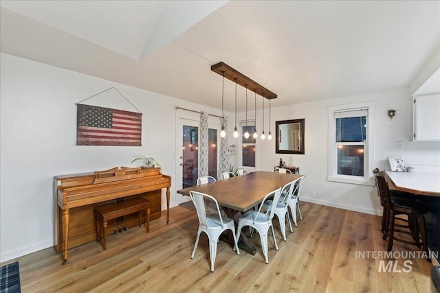 dining space featuring baseboards and light wood-type flooring