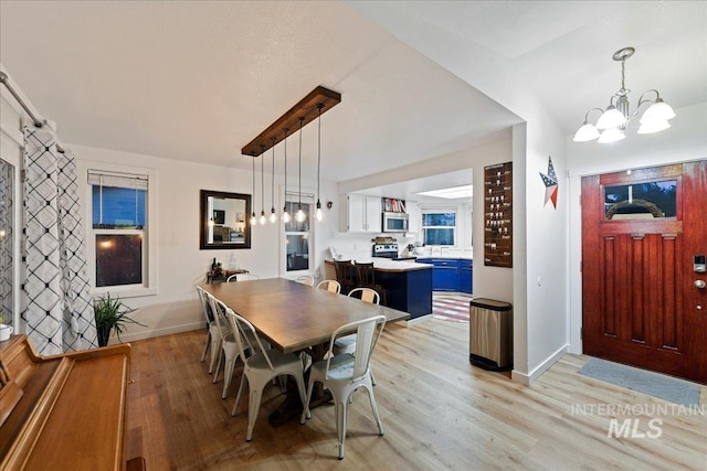 dining area featuring baseboards, an inviting chandelier, and light wood finished floors