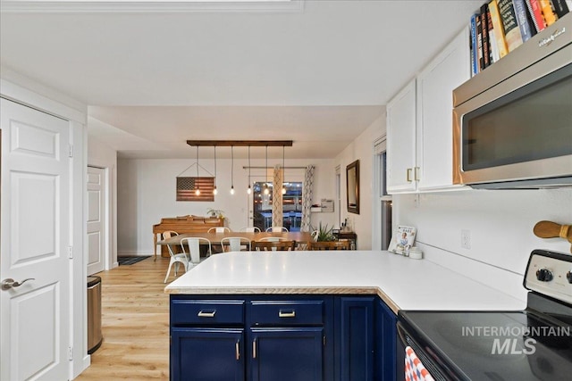kitchen with electric range, a peninsula, light countertops, stainless steel microwave, and blue cabinets