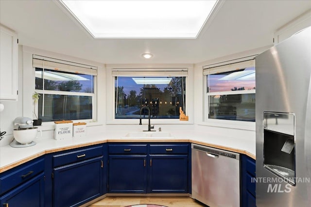 kitchen with light countertops, a sink, blue cabinetry, and stainless steel appliances