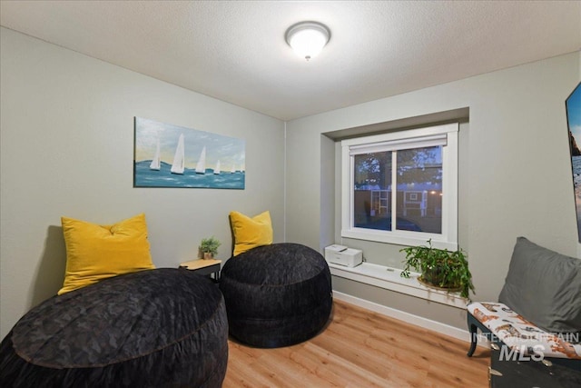 sitting room featuring baseboards and light wood finished floors
