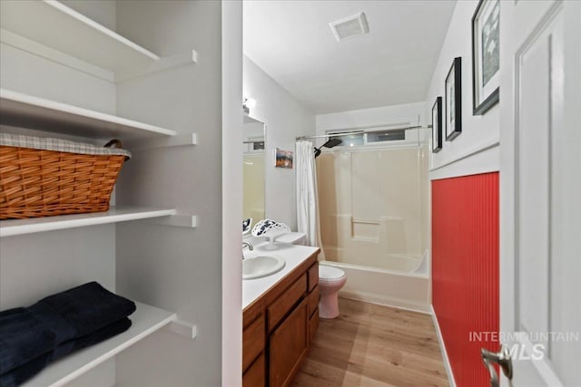 bathroom featuring visible vents, wood finished floors, vanity, toilet, and shower / bath combo with shower curtain