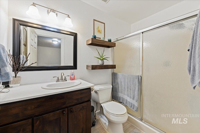 full bathroom featuring toilet, a shower stall, wood finished floors, and vanity