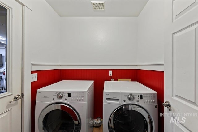 washroom with a wainscoted wall, laundry area, separate washer and dryer, and visible vents