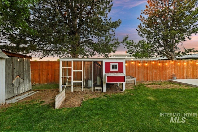 outdoor structure at dusk with an outdoor structure, exterior structure, a fenced backyard, and a yard
