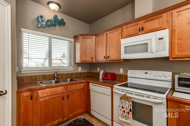 kitchen with white appliances, sink, and light tile patterned flooring