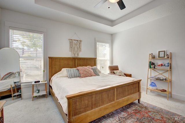 bedroom featuring a tray ceiling, ceiling fan, and light colored carpet