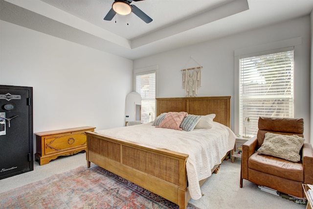 bedroom with a raised ceiling, ceiling fan, and carpet flooring